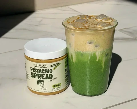 Iced matcha latte in a glass topped with a thick layer of pistachio cream cold foam